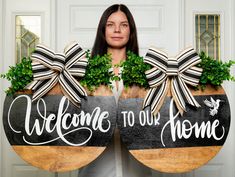 a woman holding two welcome to our home signs