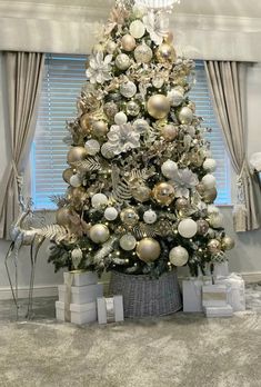 a white christmas tree with gold and silver ornaments in a living room decorated for the holidays