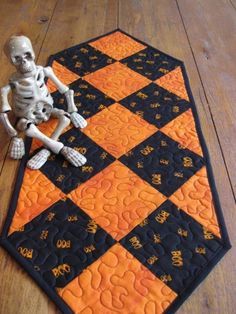 a skeleton sitting on top of an orange and black rug