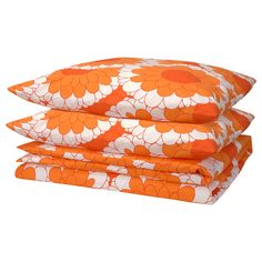 three orange and white flowered pillows stacked on top of each other in front of a white background