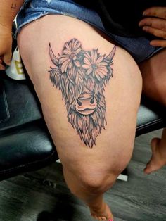 a woman's thigh with a cow tattoo on the side and flowers in her hair