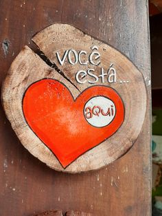 a piece of wood with an orange heart painted on it that says voce esta