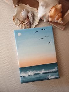 an acrylic painting with sea shells and seashells on the table next to it