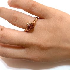 a woman's hand with a gold ring on top of her finger and an orange stone in the middle