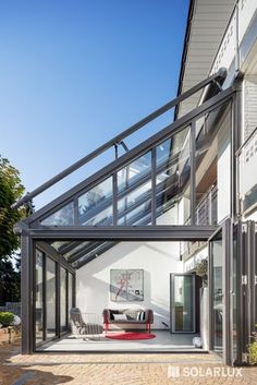 an outdoor living area with glass walls and metal railings on the side of a house