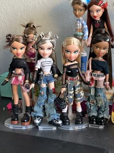 a group of dolls standing next to each other on a table with toys in the background