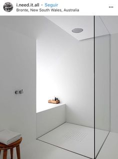 a white bathroom with a glass shower door and stand up shower head in the corner