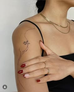 a woman's arm with a flower tattoo on her left shoulder, and a gold chain around her neck