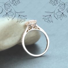 a diamond ring sitting on top of a white rock next to some leaves and flowers