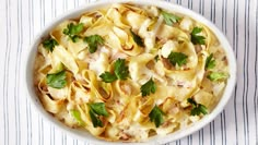 a white bowl filled with pasta covered in cheese and parsley