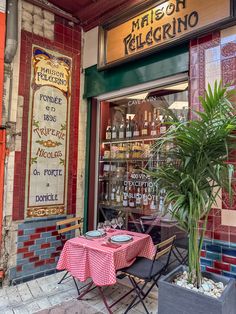 a table and chairs outside of a restaurant with a red checkered table cloth on it