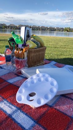 a picnic table with food and drinks on it, near the water's edge