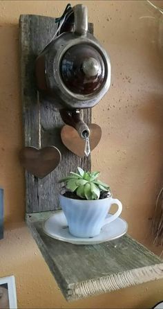 a teacup with a plant in it is hanging on the wall next to a phone