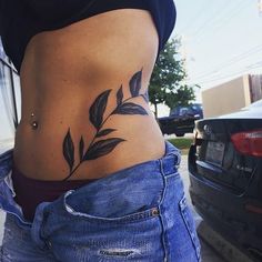 a woman's stomach with leaves on it and a car parked in the background