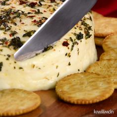 a person cutting cheese with a knife on top of crackers