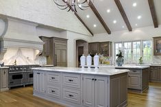 a large kitchen with wooden floors and gray cabinets, an island countertop and chandelier