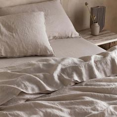 an unmade bed with white sheets and pillows