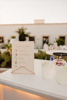 a menu sitting on top of a white table next to two glasses filled with liquid