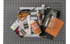 crafting supplies laid out on top of a cutting board with scissors and glues