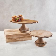 three tiered wooden cake stand with cupcakes on top and muffin tray