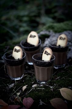 four small pots with fake marshmallows in them sitting on the ground next to leaves