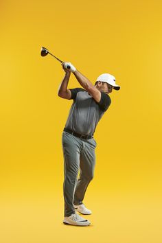 a man swinging a golf club on top of a yellow background in front of the camera