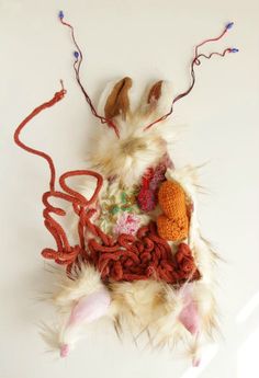 an animal made out of yarn and other items on a white surface with strings attached to it