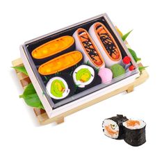 an assortment of sushi in a tray with chopsticks and vegetables on the side