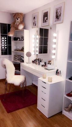 a white vanity with lights and a teddy bear