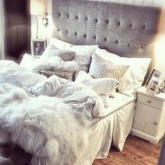 an unmade bed with fluffy blankets and pillows on it's headboard in a bedroom