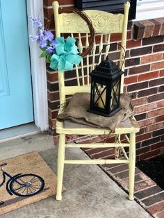 a yellow rocking chair with a black lantern and blue flowers sitting on it's seat