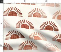 an orange and white sun print fabric with brown spots on the top, in front of a ruler