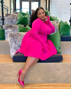 a woman in a pink dress is sitting on some stairs and posing for the camera