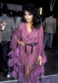 a woman in a purple dress with feathers on it