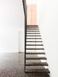 the stairs are made of metal and have black treads on them, with a pink door in the background