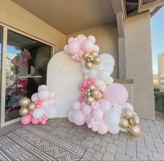 a balloon arch is decorated with pink, gold and white balloons