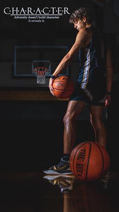 a young man holding a basketball standing on top of two orange balls in front of him