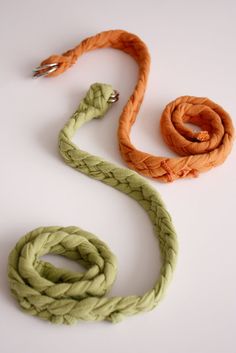 an orange and green rope on a white surface with a metal hook in the middle