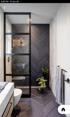 a bathroom with black and white herringbone tile on the floor, shower stall, toilet and sink