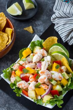 a salad with shrimp, avocado, and mango salsa on a black plate