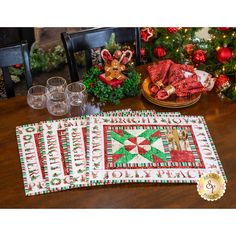 a table topped with plates and glasses next to a christmas themed place mat on top of a wooden table