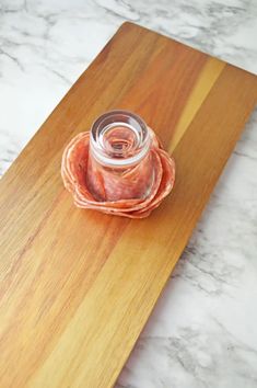 a wooden cutting board topped with a glass jar filled with food on top of it