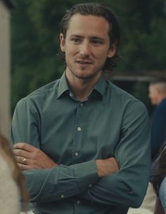 a man with his arms crossed standing in front of a woman wearing a dress shirt