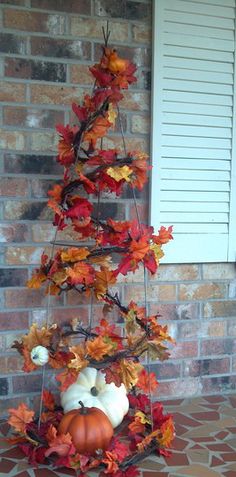 a small tree made out of leaves and pumpkins