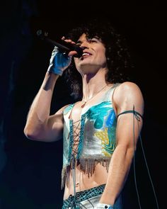 the woman is singing on stage with her hands up to her face and holding a microphone