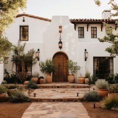 a white stucco house with potted plants and lights on the front door is shown