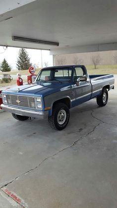 a blue truck parked in a garage next to a red fire hydrant and another car