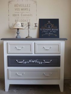 a white dresser with drawers and two candles on top