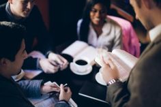 a group of people sitting around each other and one person pointing at something in the distance