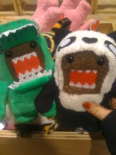 three stuffed animals are on display in a store case, one is wearing a costume and the other has a mouth